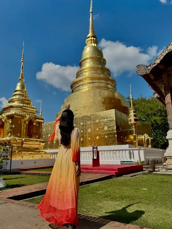 Visitantes posam ao lado do Chedi Dourado, admirando sua imponente torre dourada, que reluz magnificamente sob o sol
