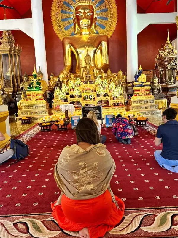 Fiéis em oração diante do Buddha Sihing, envoltos na serenidade do Wat Phra Singh