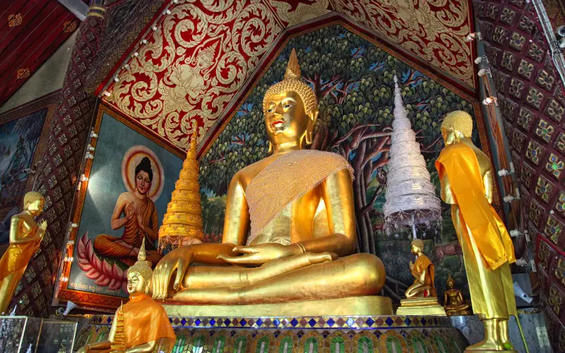 Figuras douradas de Buda sentam-se pacificamente no salão sagrado Wat Suan Dok.