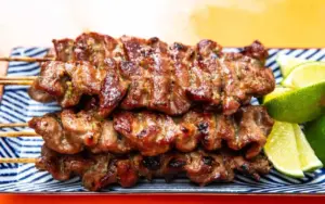 Prato Descrição e Preço
Pad Thai
Macarrão de arroz frito com ovo, camarão ou frango, molho de tamarindo e amendoim. É doce, azedo e salgado, bem gostoso!
Preço: 60 THB - 100 THB (10 BRL - 16 BRL)
Som Tum (Salada de Mamão Verde)
Salada de mamão verde com tomate e frango grelhado. É doce, azeda e um pouco picante, parecida com nossa salada, mas com um toque especial.
Preço: 50 THB - 80 THB (9 BRL - 14 BRL)
Khao Soi
Macarrão com curry de coco, frango ou carne. É cremoso, levemente picante e parece um ensopado caseiro com um sabor especial.
Preço: 80 THB - 120 THB (14 BRL - 20 BRL)
Satay
Espetinhos de frango ou porco com molho de amendoim. Parece nosso churrasquinho, mas com um toque tailandês.
Preço: 40 THB - 60 THB (por 3 espetinhos) (7 BRL - 10 BRL)
Mango Sticky Rice
Arroz doce com manga e leite de coco. Parece com o que a gente conhece, mas é incrivelmente gostoso!
Preço: 50 THB - 80 THB (9 BRL - 14 BRL)
Sorvete de Coco
Sorvete de coco com amendoim e arroz doce. É leve, perfeito para o calor, bem parecido com o nosso.
Preço: 40 THB - 60 THB (7 BRL - 10 BRL)
Porco Grelhado