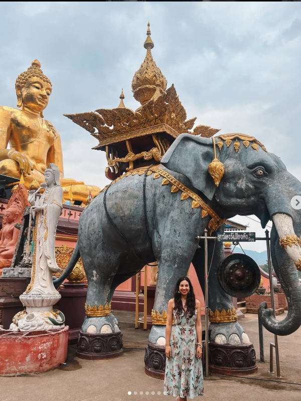 Visitante sorri entre Budas e elefantes dourados