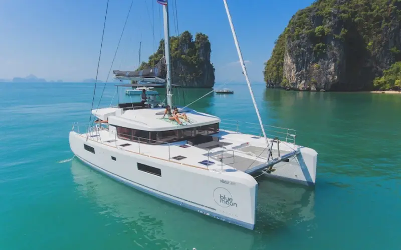 Catamarã cruza águas calmas em Phuket com paisagem