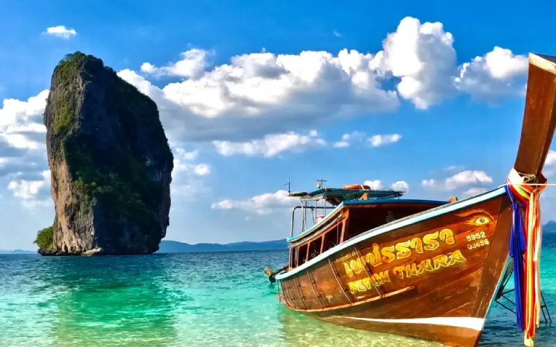 Barco tailandês desliza por águas turquesa