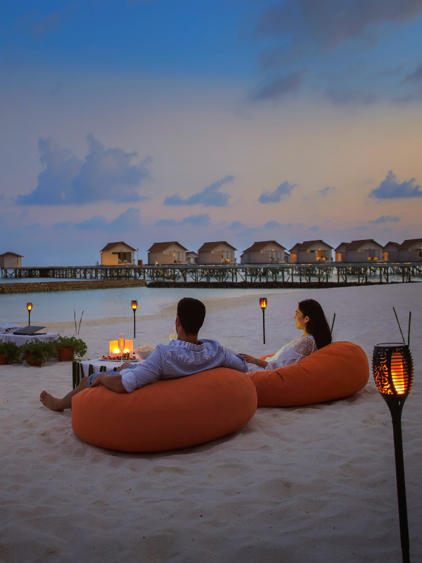 Casais desfrutam o pôr do sol romântico à beira-mar