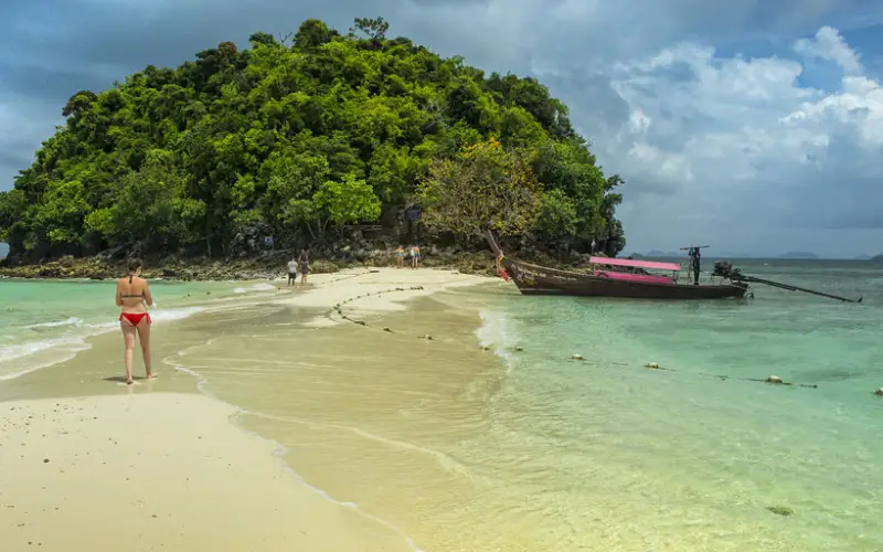 Exploradores caminham pela faixa de areia entre ilhas