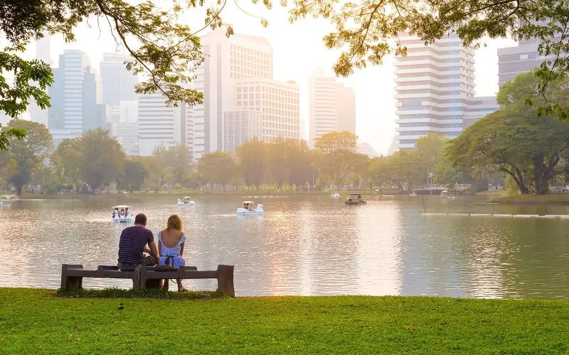Casais relaxam no verde tranquilo do Parque Lumpini