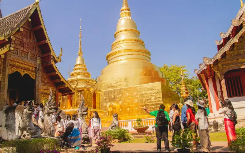 Pessoas exploram o Wat Chedi Luang sagrado e calmo