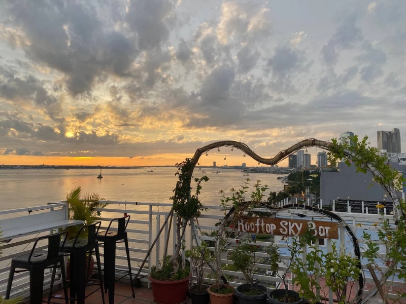 Vista noturna da Sisowath Quay, com rio iluminado e bares rooftop animados