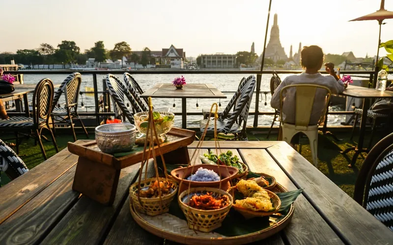Ambiente elegante do Rongros Bangkok, com vista direta para o Wat Arun às margens do rio Chao Phraya