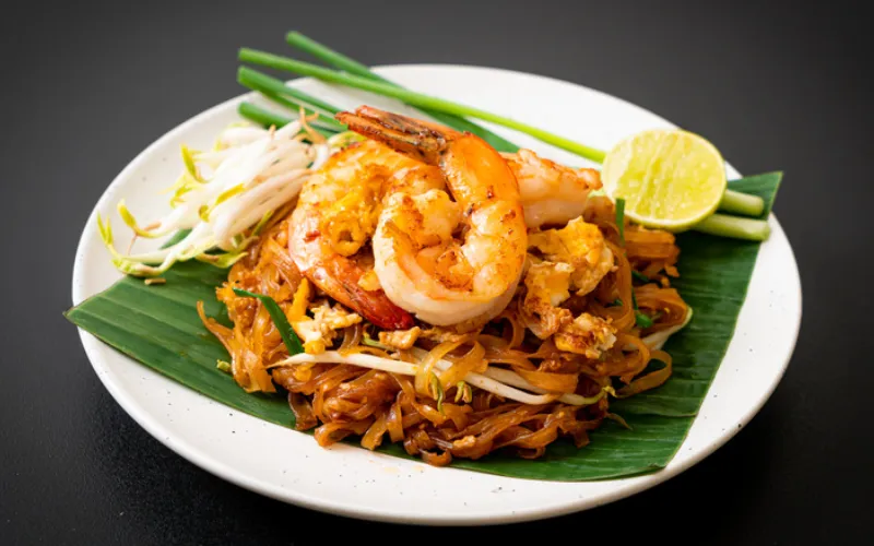 Pad Thai, um dos pratos mais famosos da culinária tailandesa, preparado com macarrão de arroz salteado, camarão, ovos e amendoim