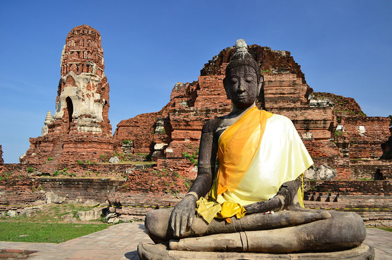 A icônica cabeça de Buda entrelaçada nas raízes de uma árvore no Wat Phra Mahathat, um dos símbolos mais famosos de Ayutthaya