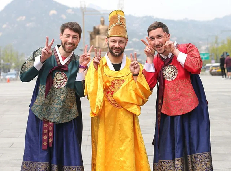 Visitantes vestindo Hanbok tradicional caminhando pelos pátios coloridos do Palácio Gyeongbokgung em Seul